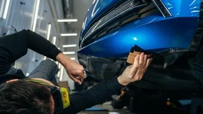 Man repairing damaged car at auto body shop